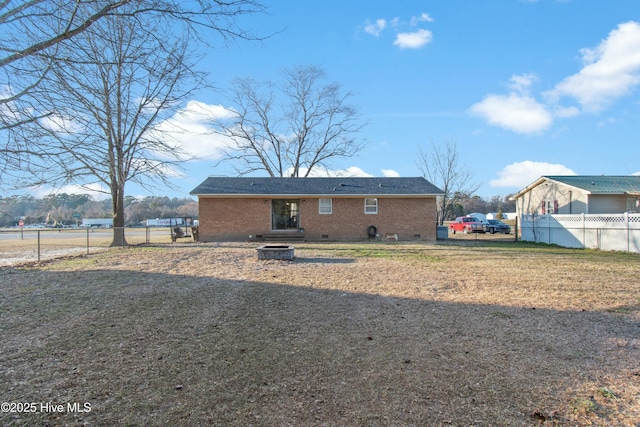 view of front of house featuring brick siding, crawl space, and fence