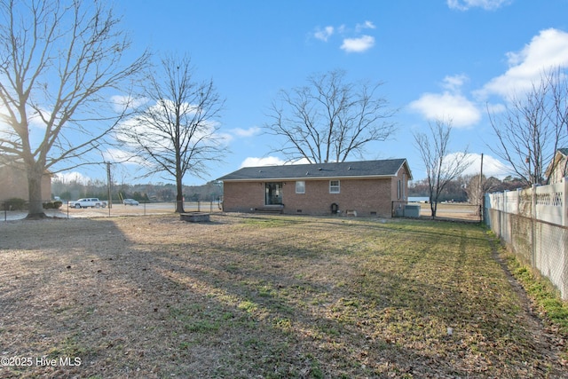 back of property featuring a yard, crawl space, brick siding, and fence