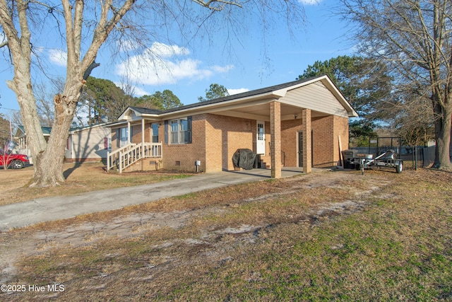 view of front of property with driveway, brick siding, crawl space, fence, and a front yard