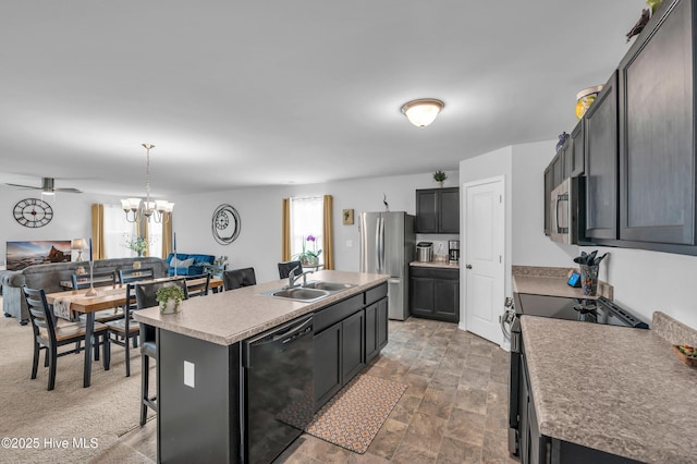 kitchen with a wealth of natural light, black appliances, a kitchen island with sink, and a sink