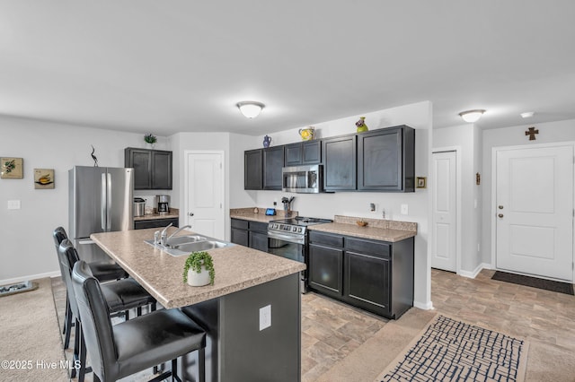 kitchen featuring a breakfast bar area, baseboards, a sink, stainless steel appliances, and light countertops