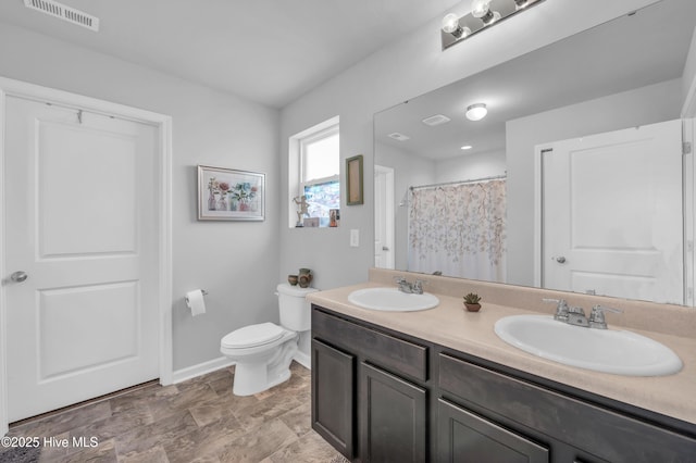 bathroom featuring toilet, baseboards, visible vents, and a sink