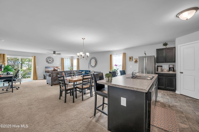 kitchen featuring open floor plan, a kitchen bar, light countertops, freestanding refrigerator, and a sink