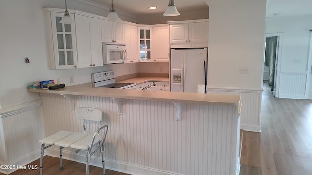 kitchen with white appliances, light countertops, hanging light fixtures, and light wood finished floors