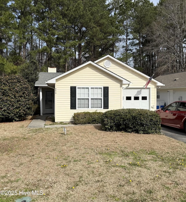 view of front facade with a garage, a chimney, and a front yard