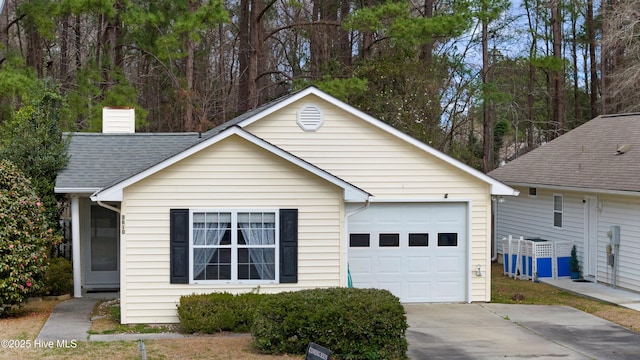 view of front of home with a shingled roof, driveway, a chimney, and a garage