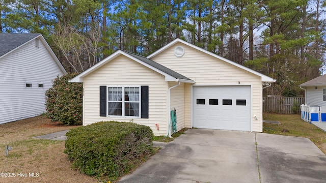 view of front of property with a garage, concrete driveway, and fence