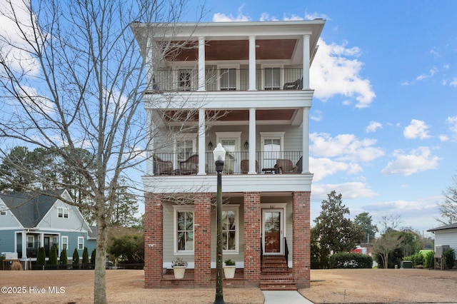 view of front of house featuring brick siding and a balcony