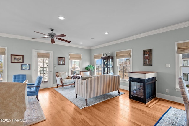 living area featuring wood finished floors, ornamental molding, a wealth of natural light, and a multi sided fireplace