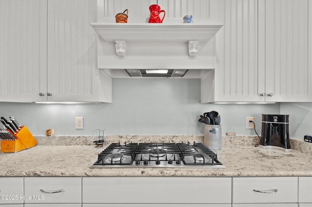 kitchen featuring light stone countertops, white cabinets, and stainless steel gas stovetop