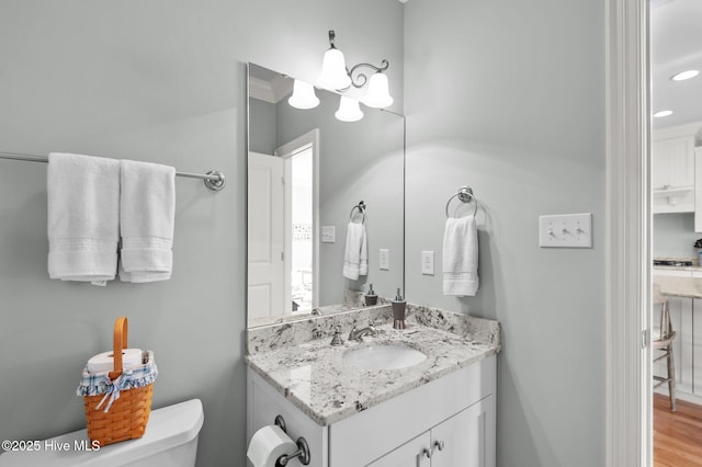 half bathroom featuring wood finished floors, vanity, and toilet