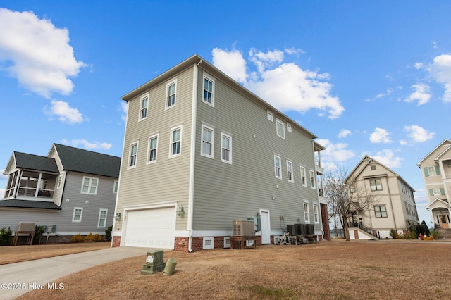 view of side of home featuring driveway, an attached garage, and central AC unit