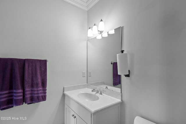 bathroom with ornamental molding, vanity, and toilet