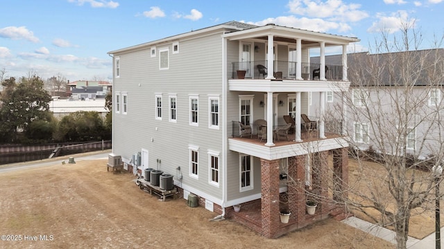 rear view of house with driveway, central AC unit, and a balcony