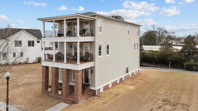 exterior space featuring dirt driveway, a porch, and a balcony