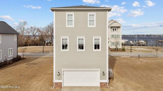 view of front of property featuring an attached garage, a water view, and concrete driveway