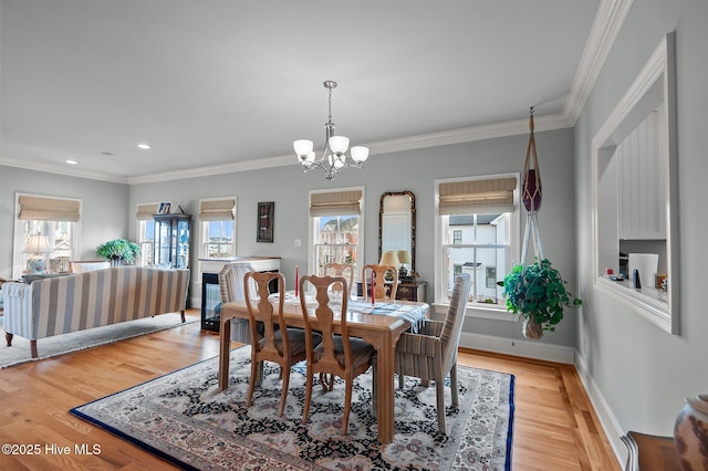 dining room with a notable chandelier, light wood finished floors, baseboards, and crown molding