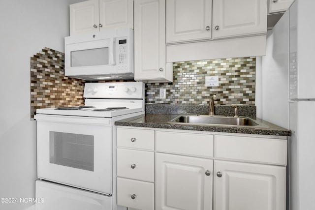 kitchen with backsplash, white appliances, dark countertops, and a sink