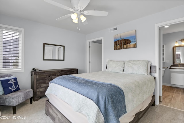 bedroom with multiple windows, a ceiling fan, visible vents, and light carpet