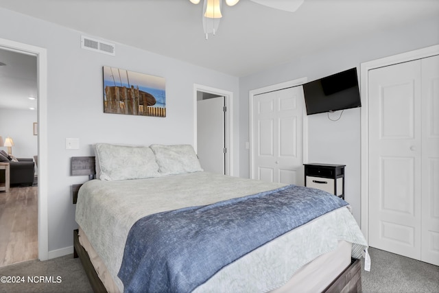 bedroom with visible vents, two closets, a ceiling fan, carpet, and baseboards