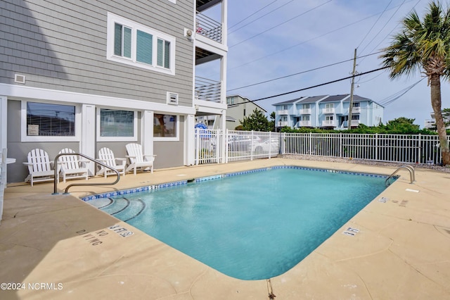 community pool with a residential view, a patio, and fence