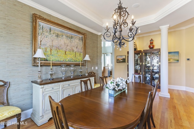 dining area featuring crown molding, light wood-style floors, and decorative columns