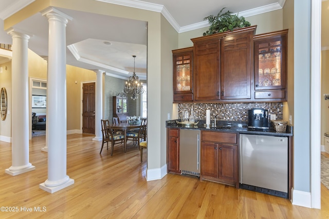 bar with light wood finished floors, crown molding, decorative backsplash, stainless steel refrigerator, and ornate columns