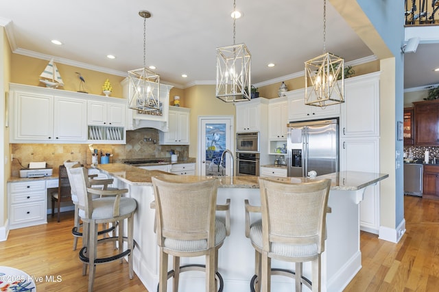 kitchen with crown molding, light wood-style flooring, hanging light fixtures, white cabinets, and stainless steel appliances