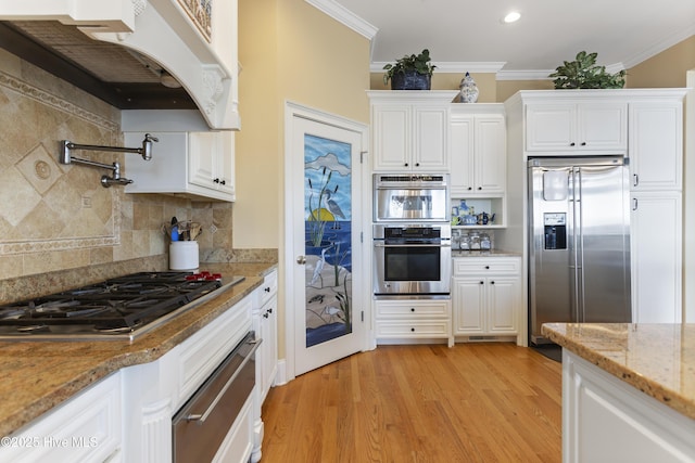 kitchen featuring crown molding, under cabinet range hood, light wood-style flooring, appliances with stainless steel finishes, and white cabinets