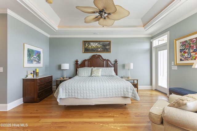 bedroom with a raised ceiling, crown molding, and light wood finished floors