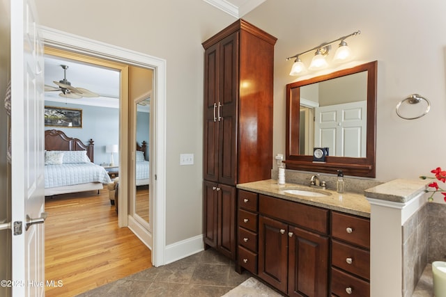 ensuite bathroom with vanity, wood finished floors, baseboards, ensuite bath, and ornamental molding