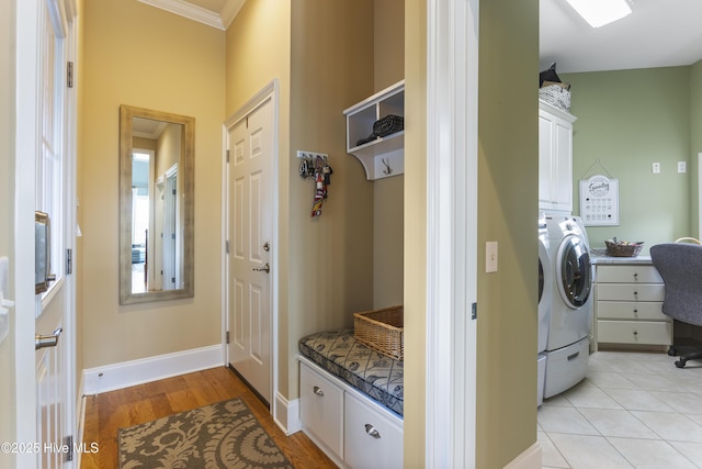 laundry area featuring light wood finished floors, baseboards, washing machine and dryer, ornamental molding, and cabinet space