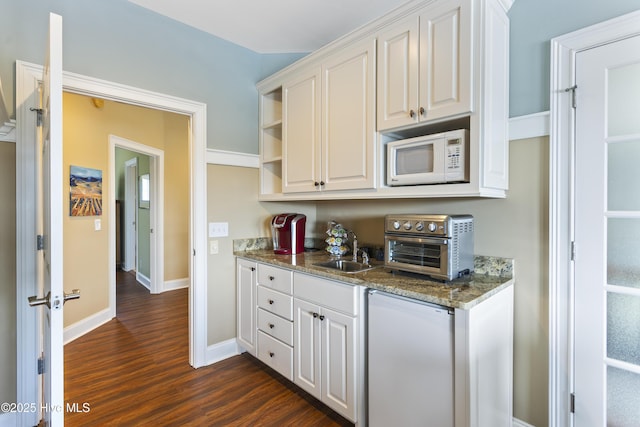 kitchen with a sink, dark wood finished floors, fridge, white cabinets, and white microwave