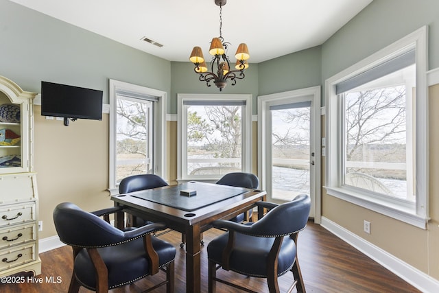 dining area with an inviting chandelier, dark wood-style floors, visible vents, and baseboards