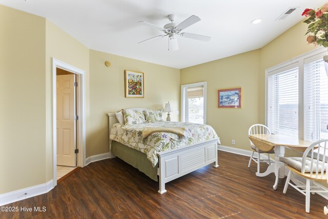 bedroom featuring visible vents, multiple windows, baseboards, and wood finished floors