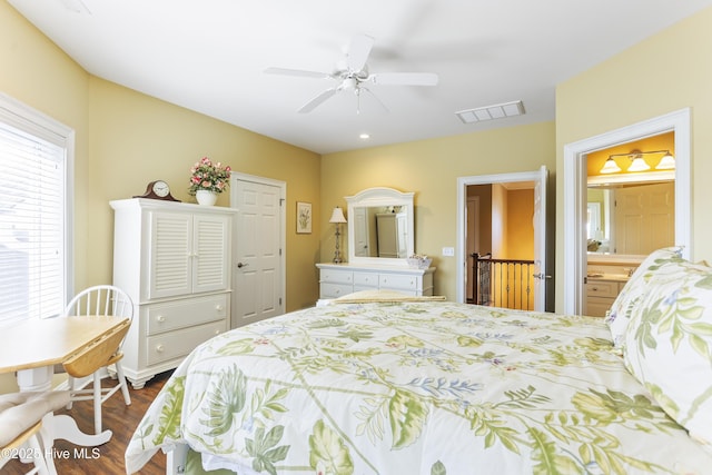 bedroom featuring dark wood finished floors, visible vents, ensuite bath, and ceiling fan