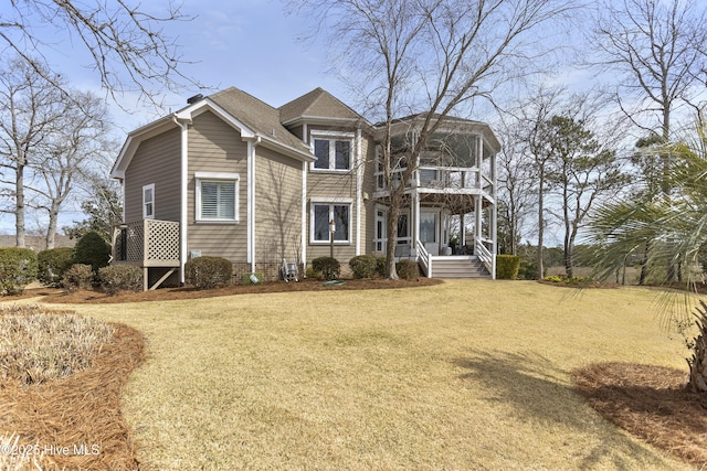 view of front of house featuring a front yard, a balcony, and roof with shingles