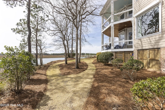 view of yard with stairs, a balcony, and a water view