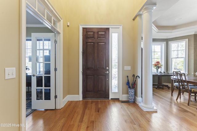 foyer featuring decorative columns, baseboards, light wood-type flooring, and ornamental molding