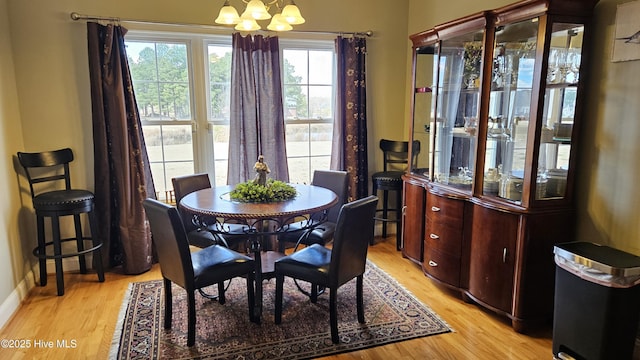 dining space with a chandelier, light wood-style flooring, and baseboards