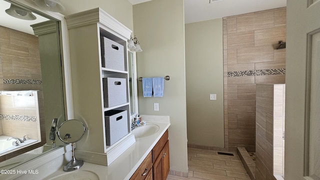 bathroom with tiled shower, vanity, and baseboards