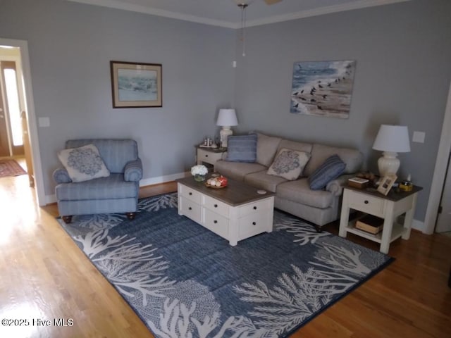 living area featuring baseboards, wood finished floors, and crown molding