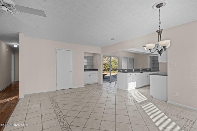 unfurnished living room with light tile patterned flooring, a sink, a textured ceiling, and baseboards