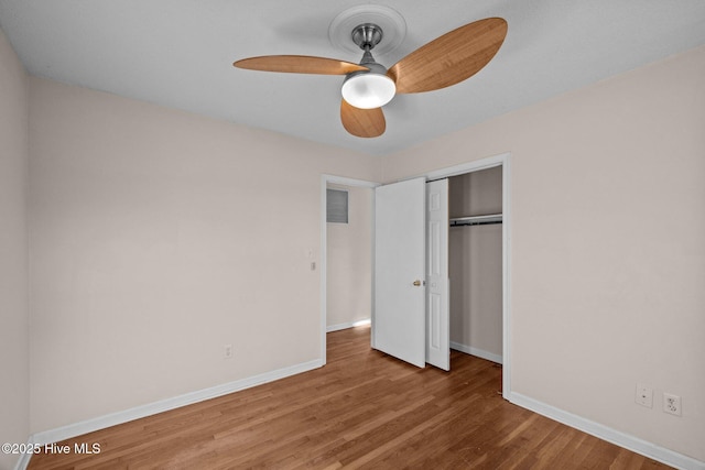 unfurnished bedroom featuring a closet, wood finished floors, visible vents, and baseboards