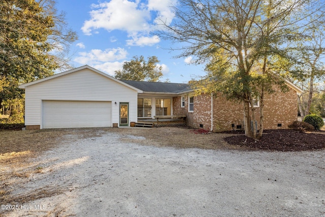 ranch-style house with driveway, brick siding, crawl space, and an attached garage