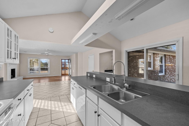 kitchen featuring dark countertops, vaulted ceiling, a sink, and stainless steel dishwasher