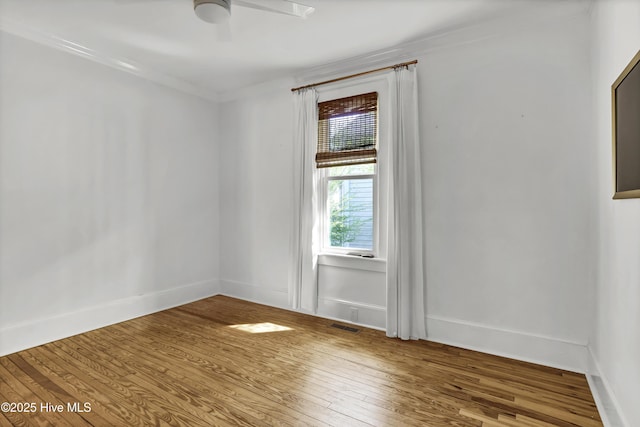 unfurnished room featuring visible vents, ornamental molding, a ceiling fan, hardwood / wood-style flooring, and baseboards