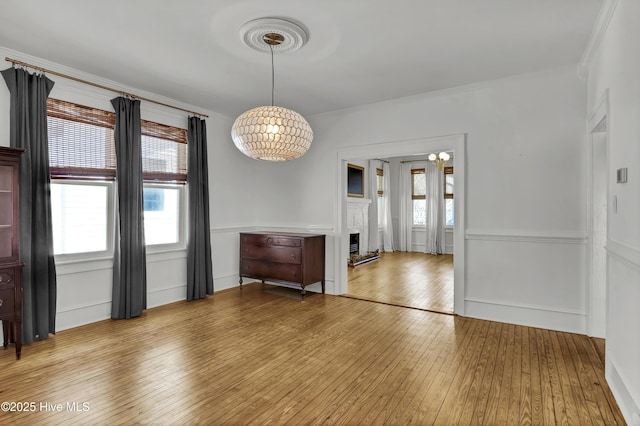unfurnished dining area with a decorative wall, crown molding, and hardwood / wood-style flooring