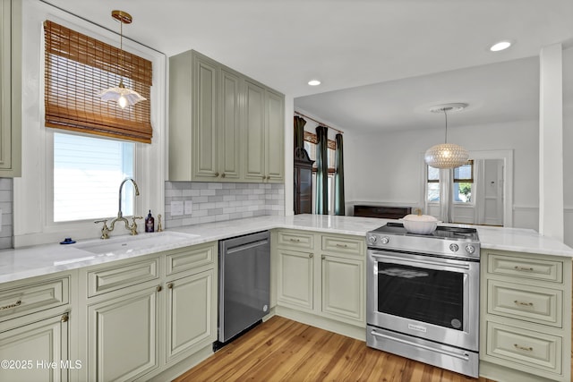 kitchen with a wealth of natural light, cream cabinetry, a sink, appliances with stainless steel finishes, and a peninsula