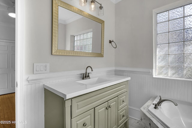 bathroom featuring a wainscoted wall, a garden tub, and vanity
